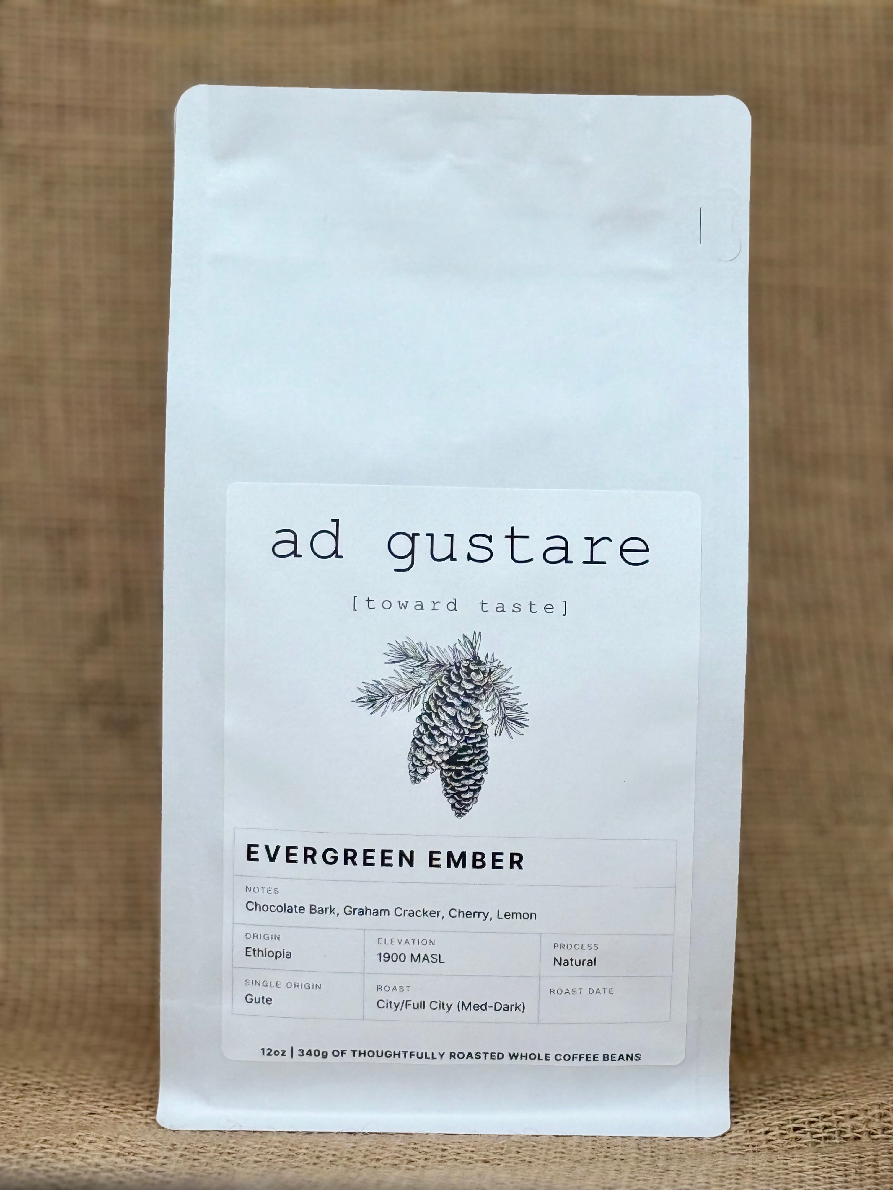 Ad Gustare Evergreen Ember Ethiopia coffee bag with minimalist white label featuring a pine cone illustration, photographed on burlap