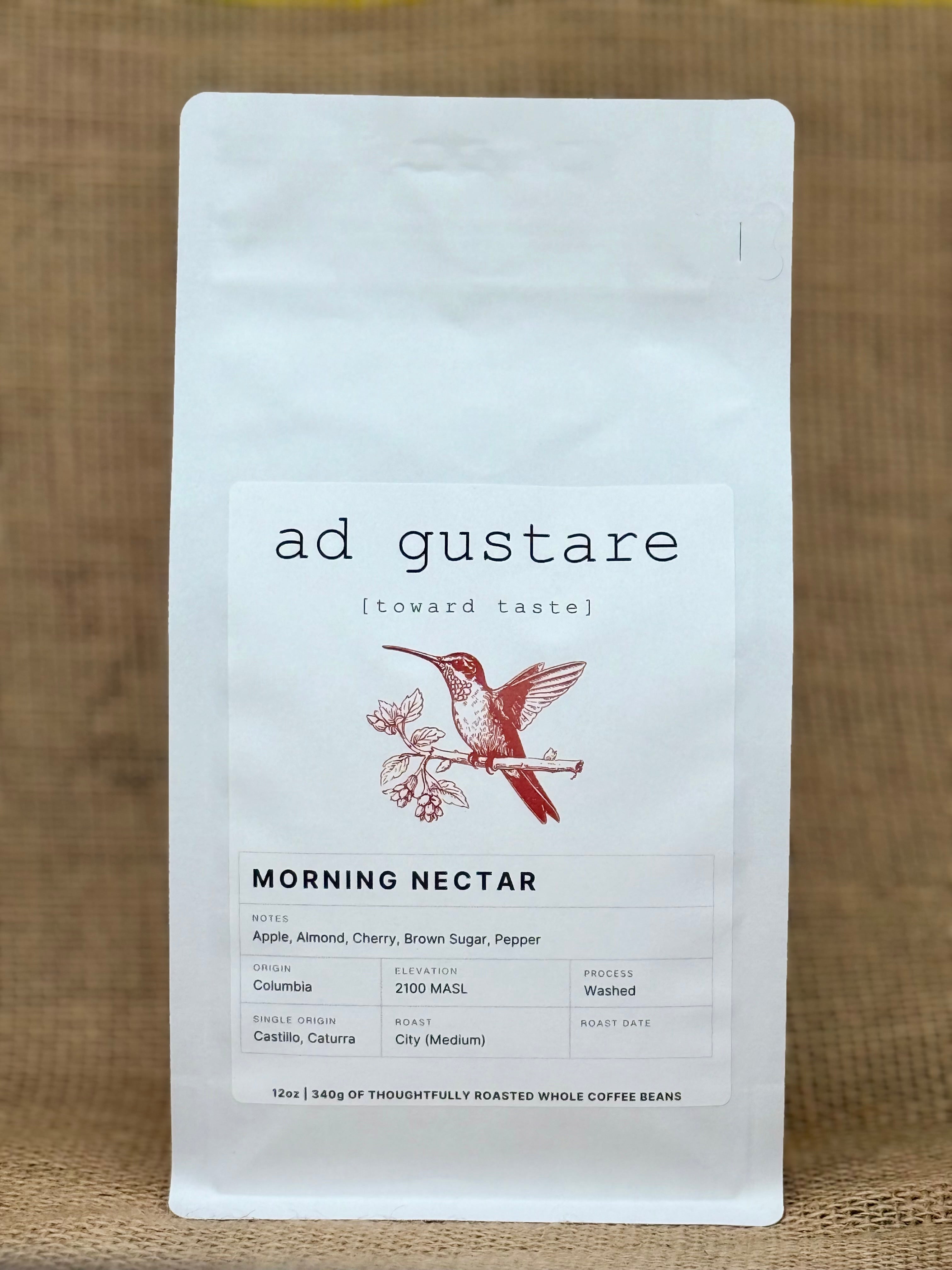 Ad Gustare Morning Nectar Colombia coffee bag with minimalist white label featuring a hummingbird illustration, photographed on burlap.